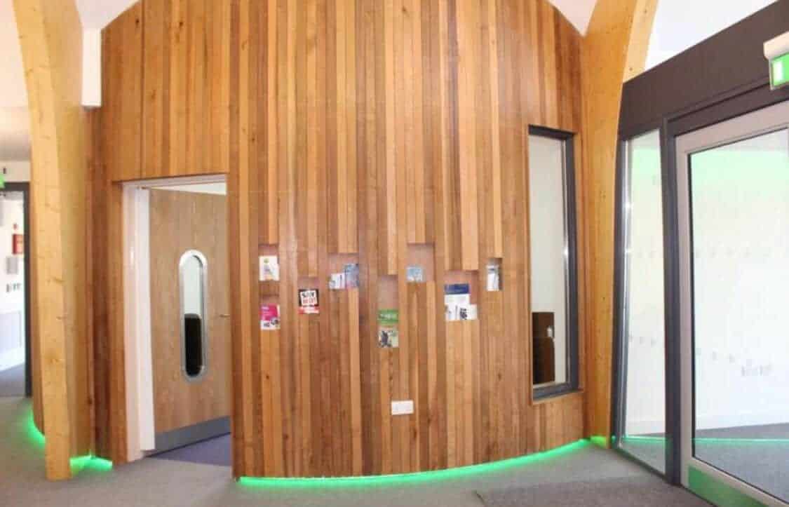 Wooden slates on the office wall with green LED strip lights